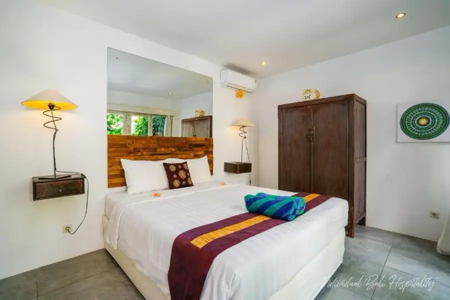 A second bedroom — teak wardrobe, cool linen