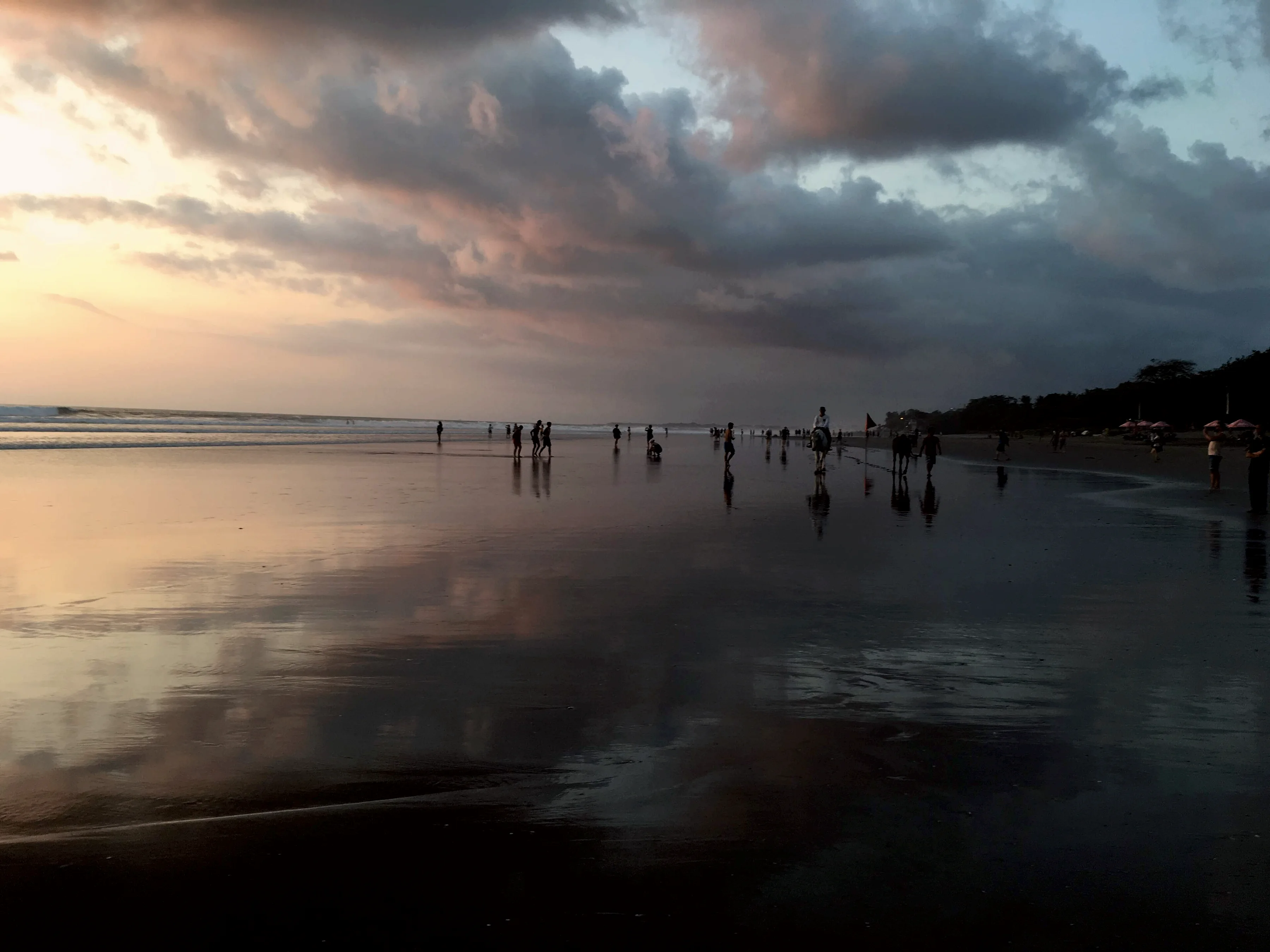Le sable mouillé reflète le ciel du soir sur la plage de Seminyak