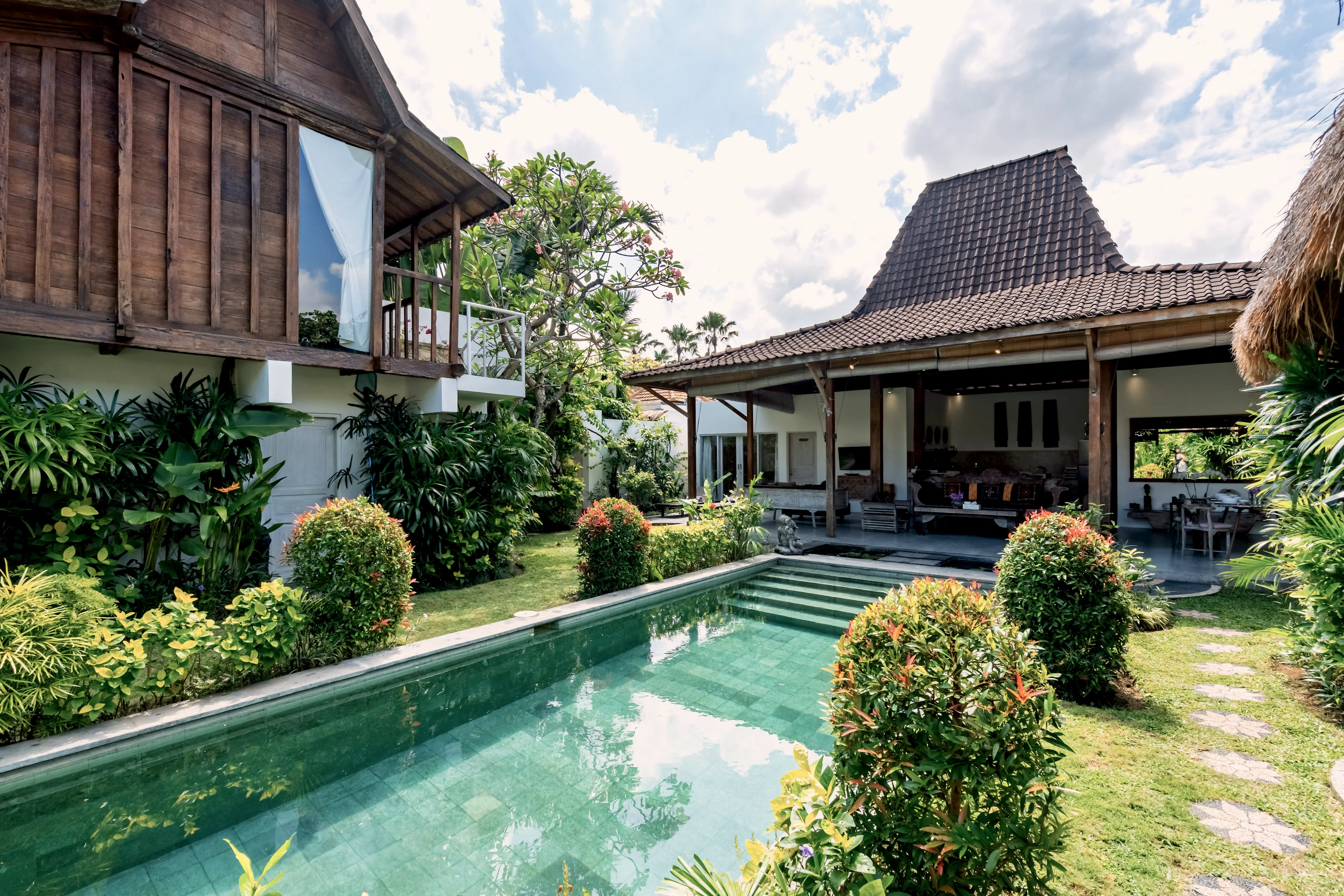 Kolam memanjang sepanjang rumah, semak terpangkas di tepinya