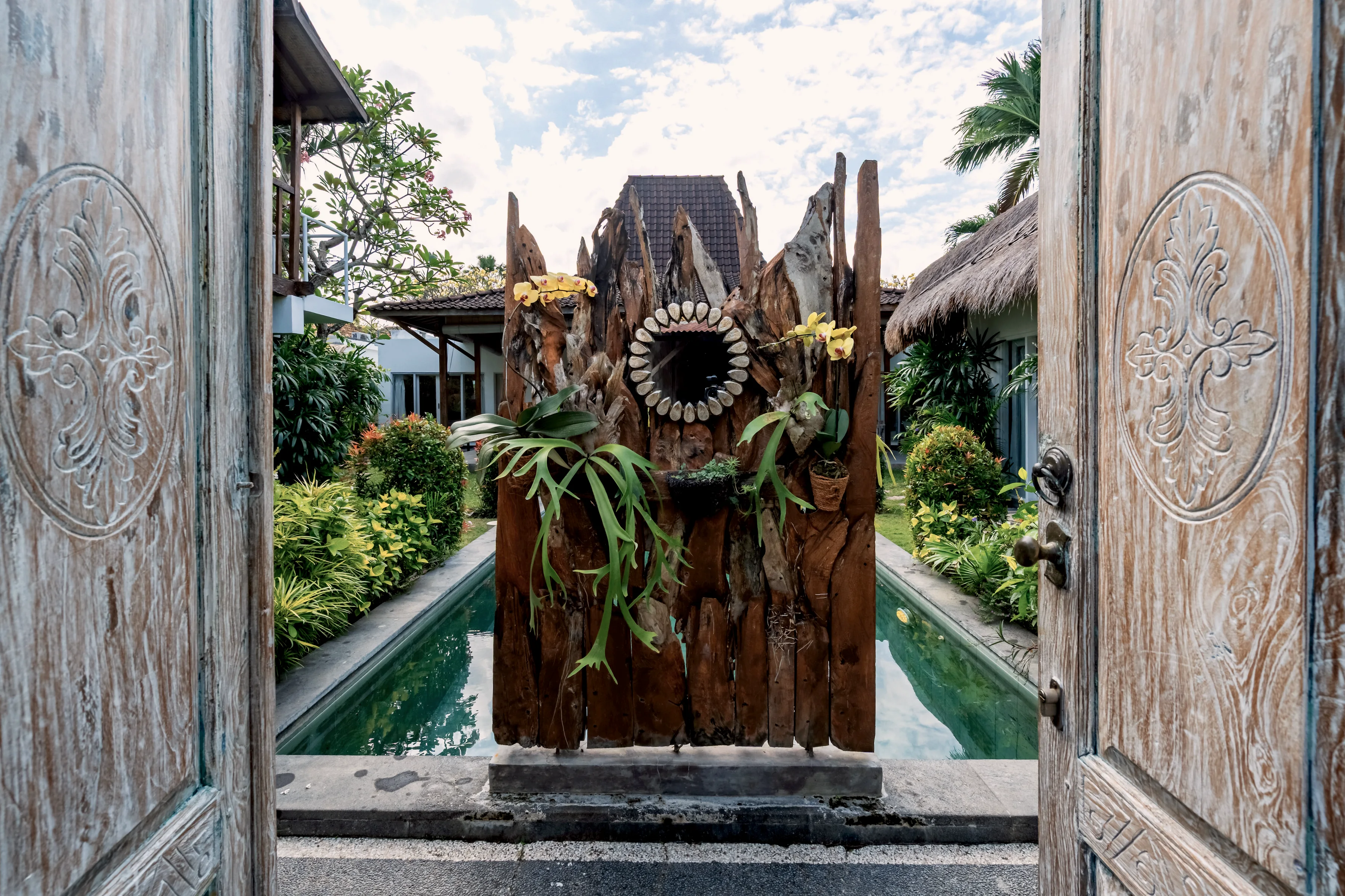 The carved timber gate at the entrance, the pool visible through it