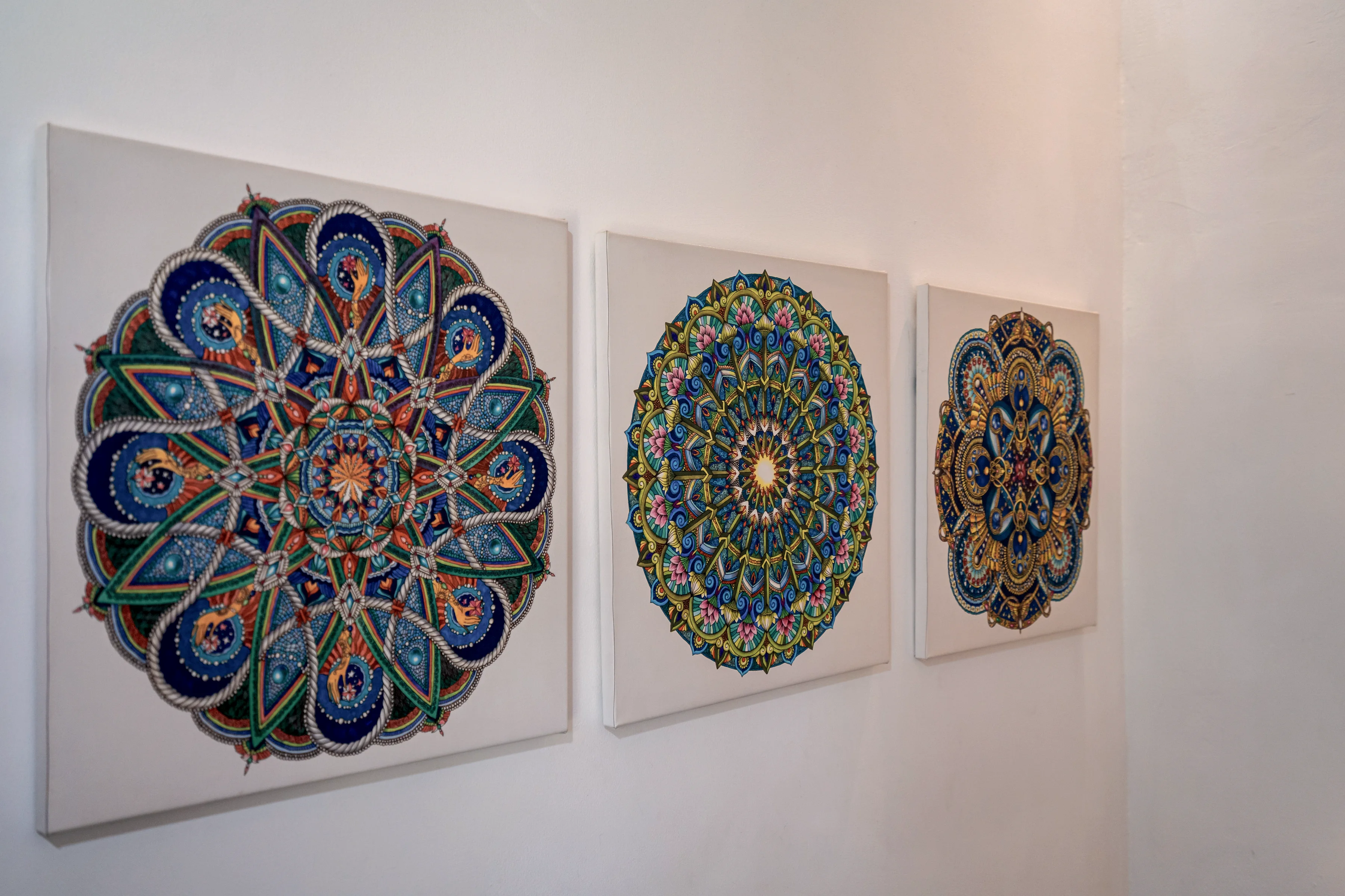 Tiga piring mandala berlukis di dinding putih