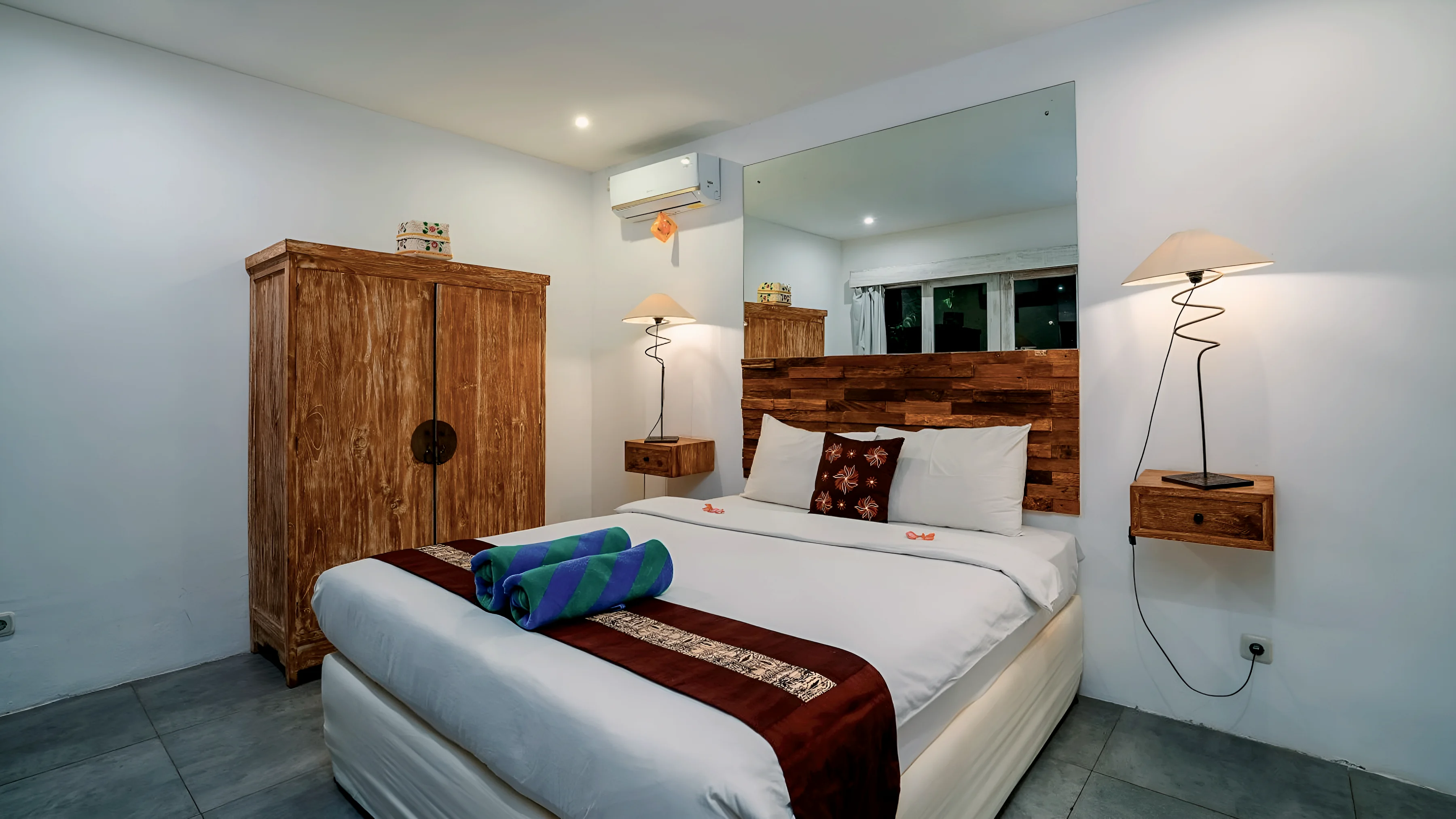 Kamar tidur putih dengan lemari jati dan ranjang ganda
