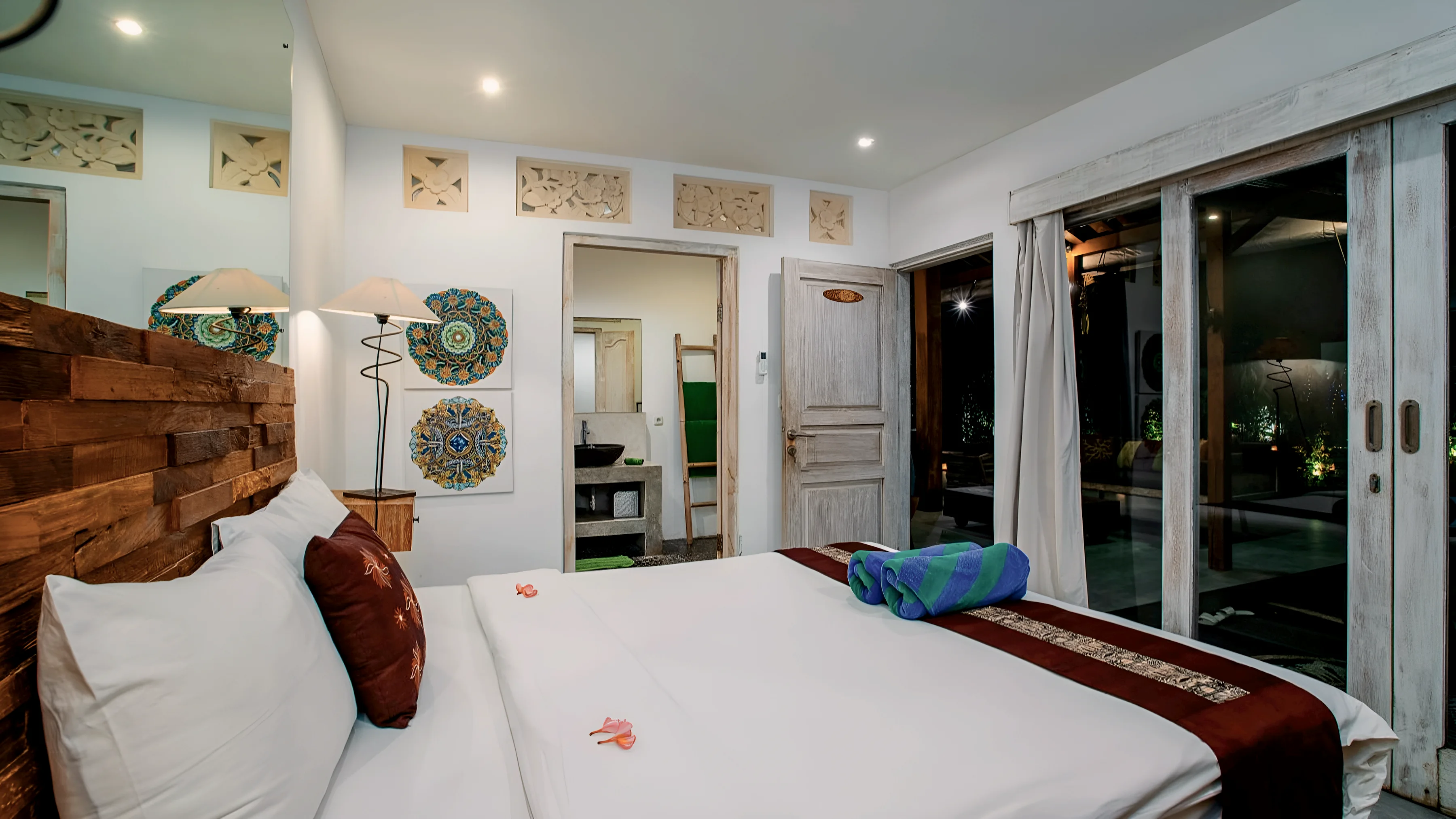 Kamar tidur dengan kepala ranjang berukir dan pintu kaca ke taman