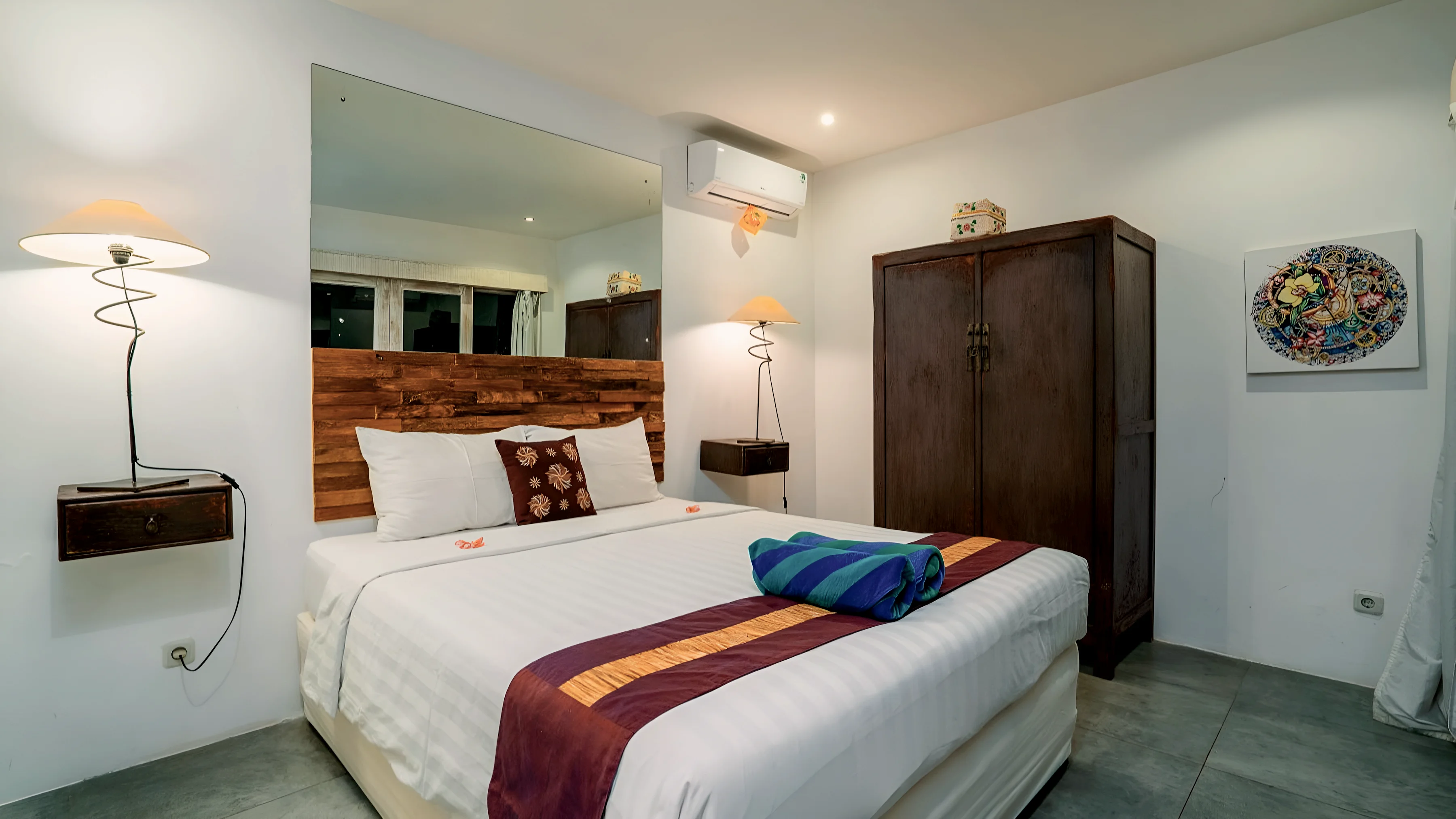 Kamar tidur putih dengan lemari gelap dan piring lukis di dinding